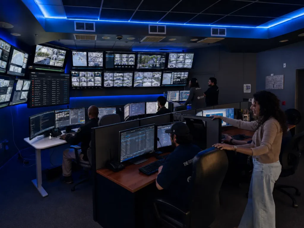 Operators in Calidad Services security operations center monitoring banks of camera feeds and TrackTik incident dashboards