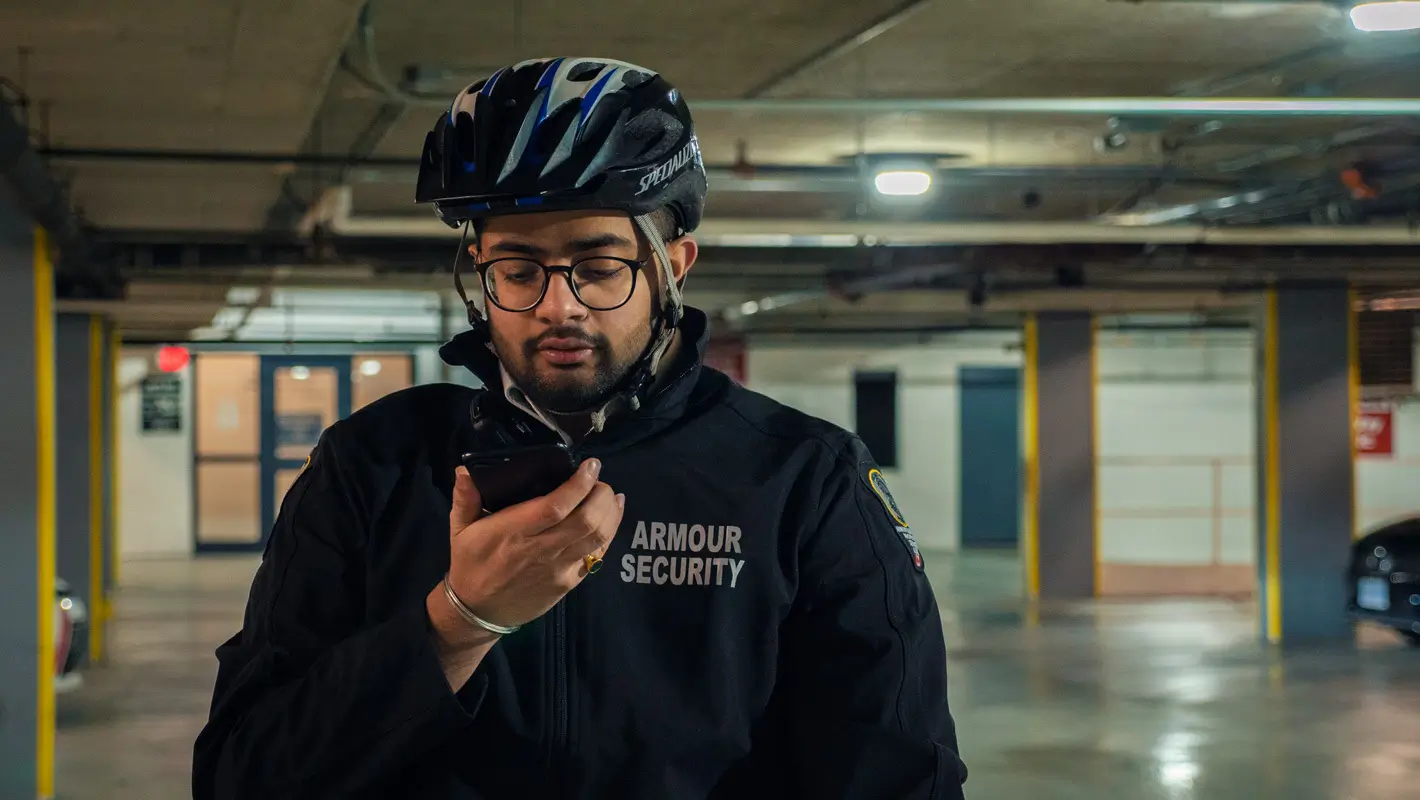 An Armour Security bike patrol officer checking a mobile device in an underground parkade