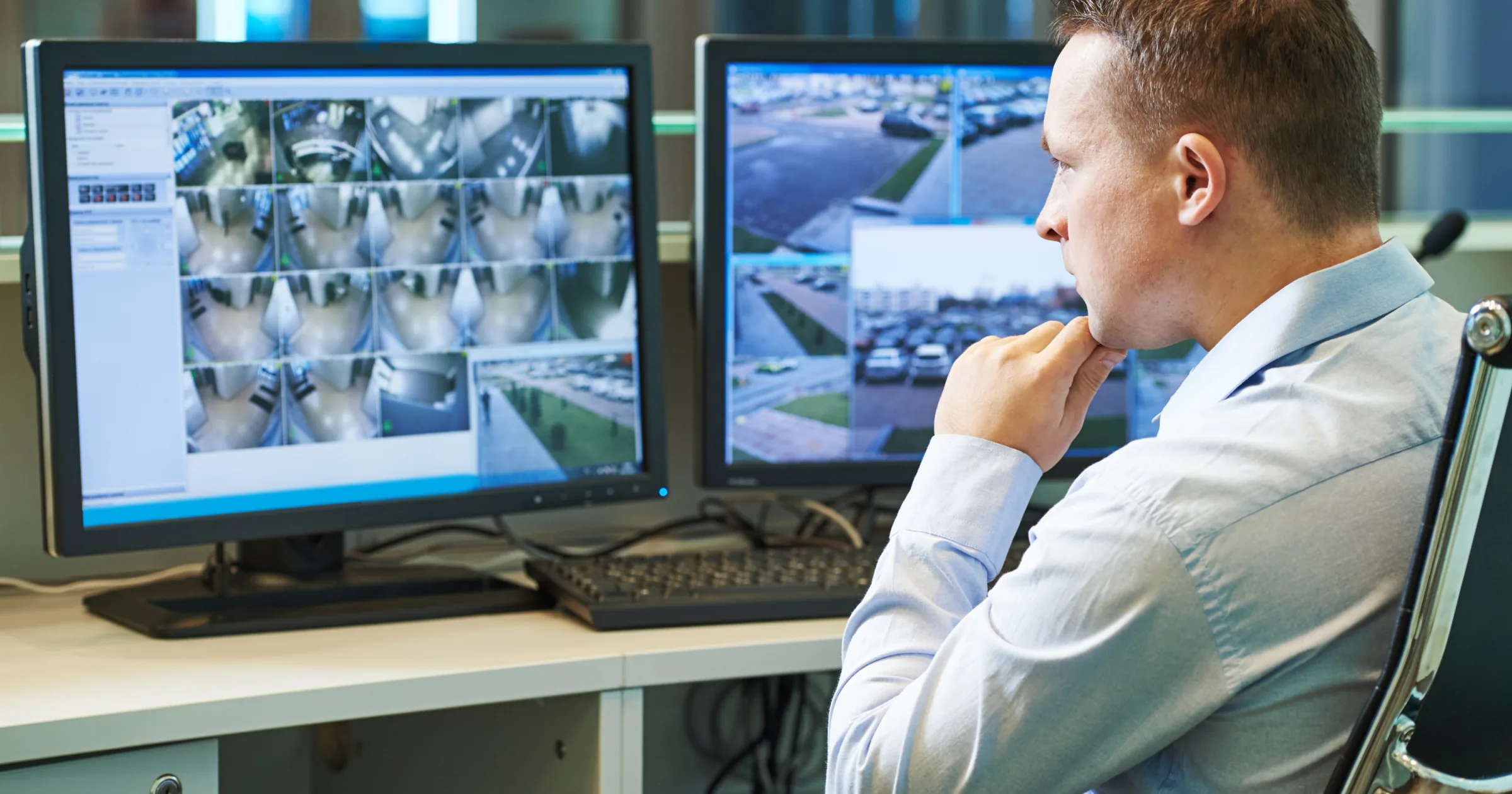 Security operations manager reviewing live surveillance camera feeds on two monitors
